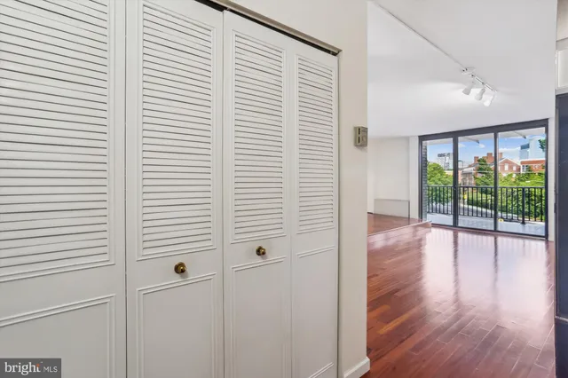a view of an empty room with wooden floor and a window