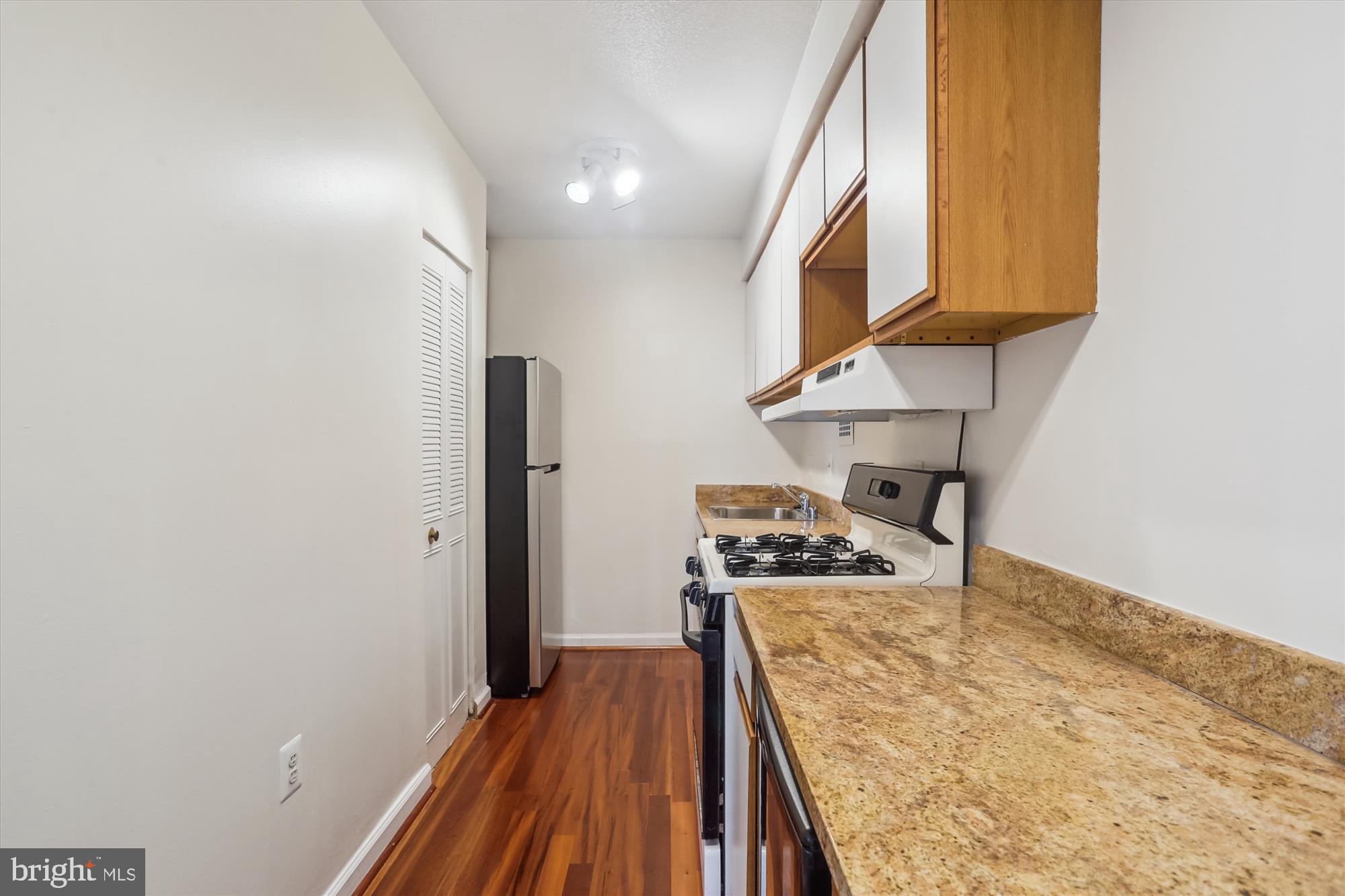 4242 East-West Highway, Unit 414 Chevy Chase, MD 20815 - Photo 20 of 66 a kitchen with wooden floor and a stove top oven