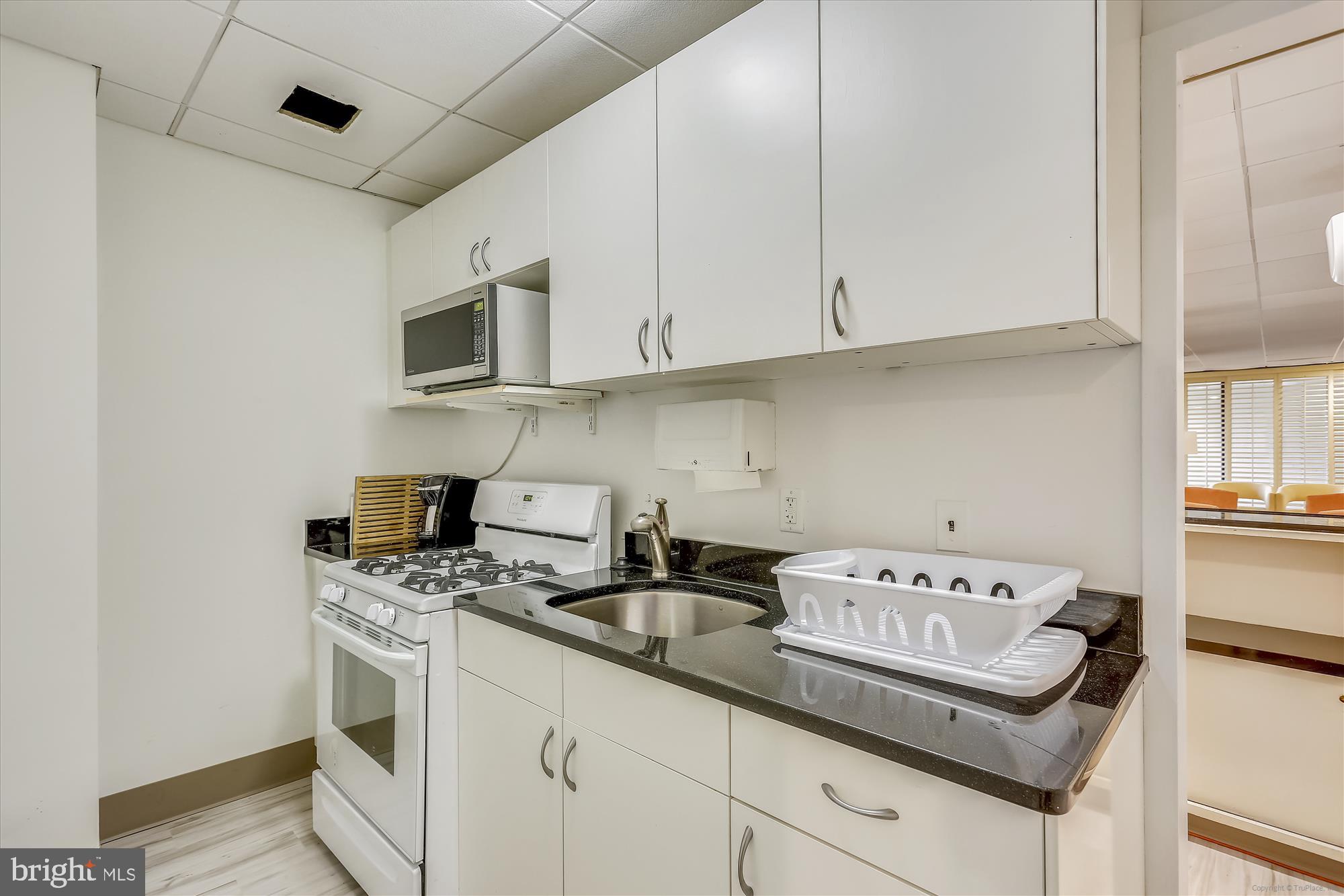 4242 East-West Highway, Unit 414 Chevy Chase, MD 20815 - Photo 45 of 66 a kitchen with stainless steel appliances granite countertop a sink a stove and a microwave