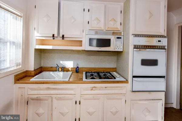 a kitchen with stainless steel appliances a sink stove and white cabinets