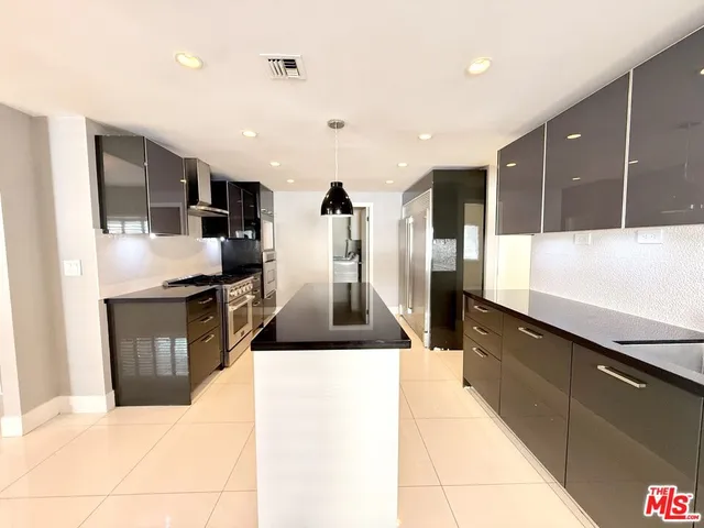 a kitchen with granite countertop a refrigerator and a stove top oven