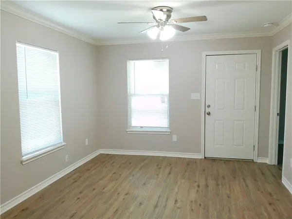 a view of an empty room with wooden floor and a window