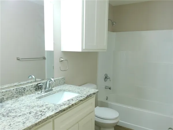 a bathroom with a granite countertop sink a toilet and shower