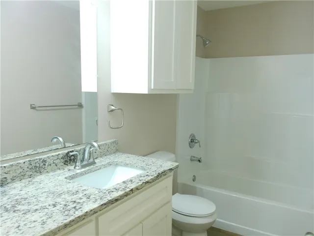 a bathroom with a granite countertop sink a toilet and shower