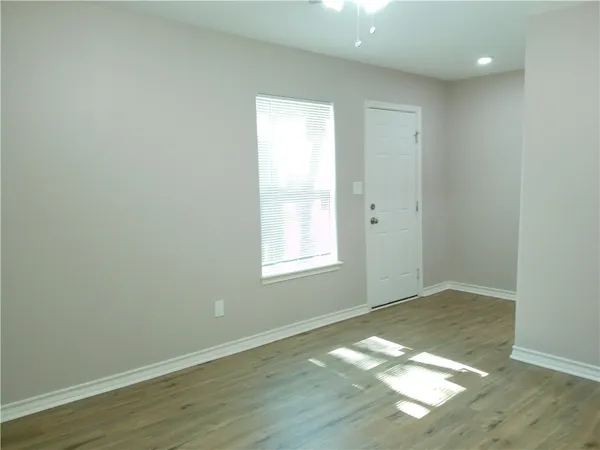 an empty room with wooden floor and windows