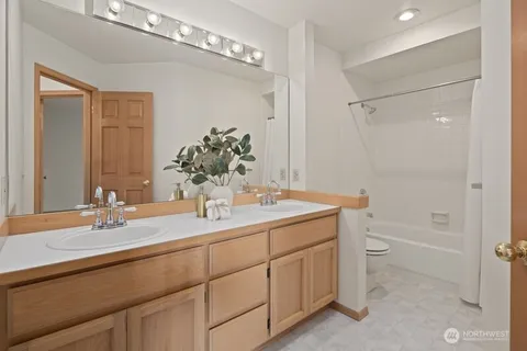 a bathroom with a sink double vanity granite tub shower and a mirror