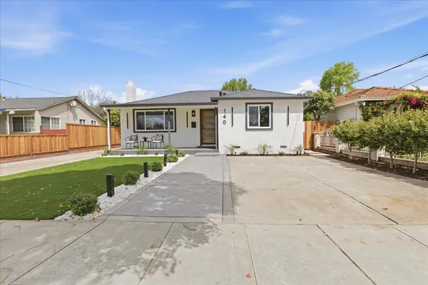 a front view of a house with a yard and potted plants