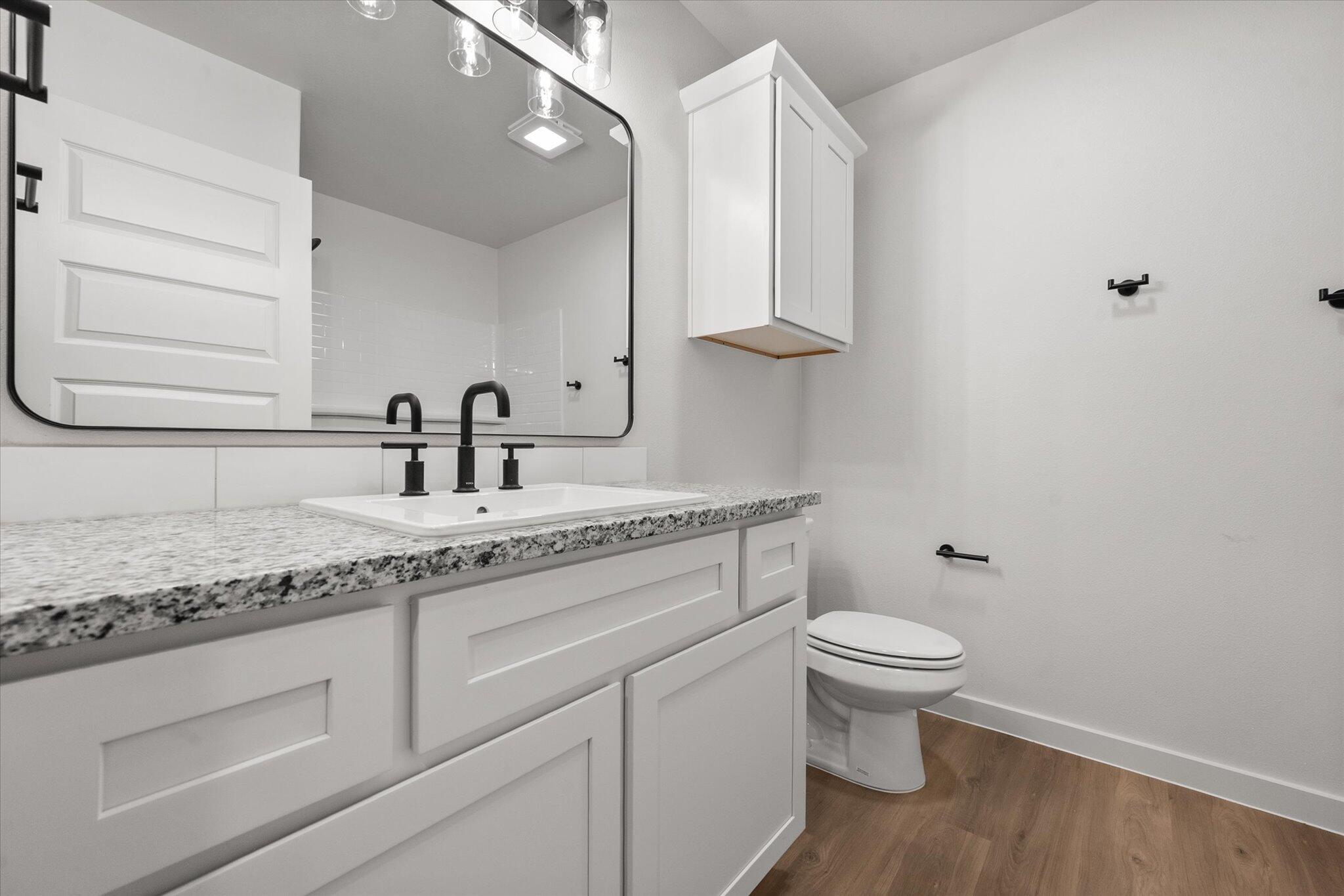 7007 56th Street Lubbock, TX 79407 - Photo 19 of 22 a bathroom with a granite countertop sink a toilet and a mirror