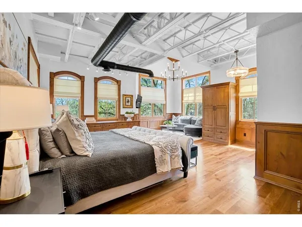 a bedroom with a large bed and wooden floor