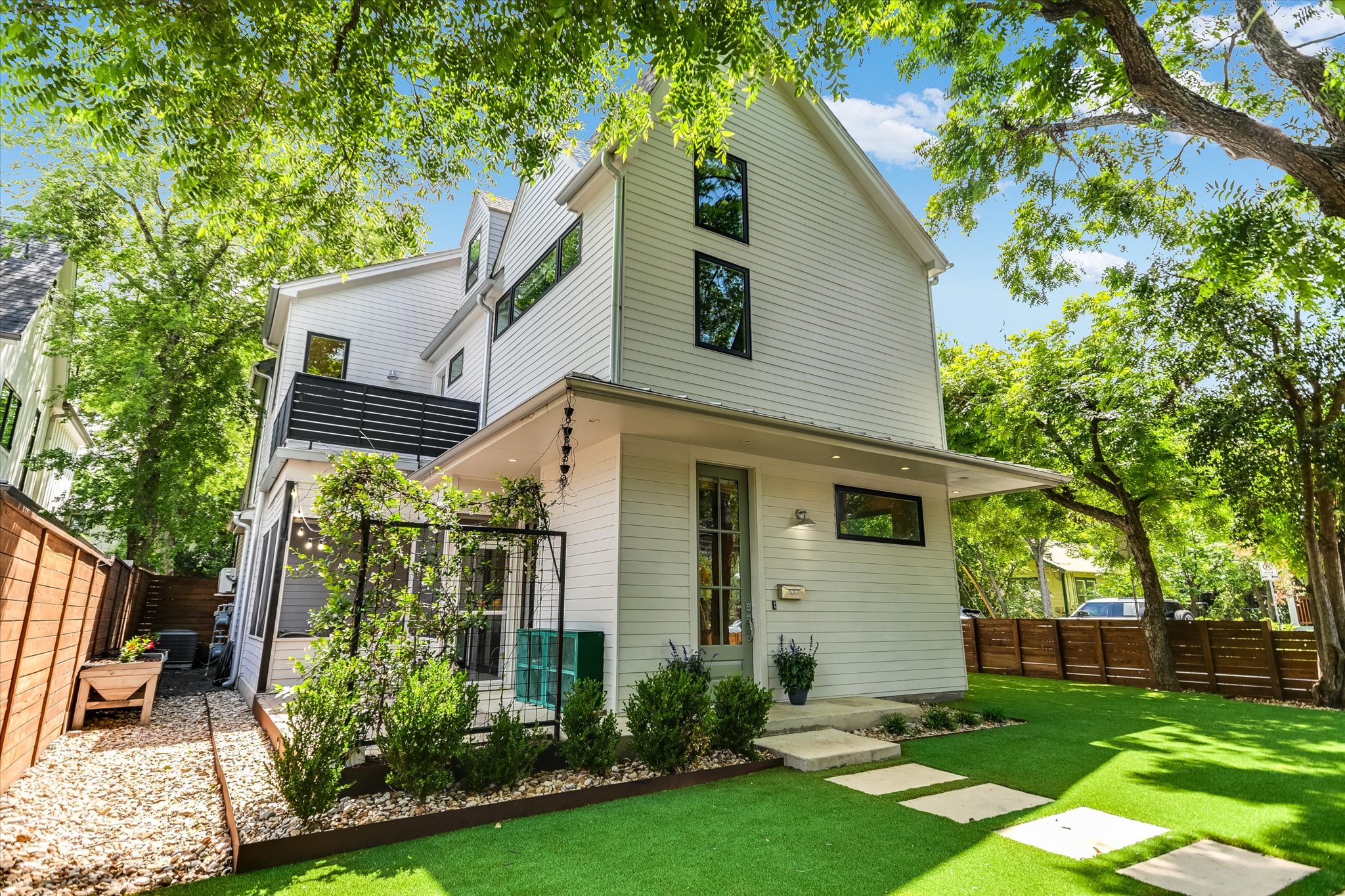 1605 Hether Street Austin, TX 78704 - Photo 3 of 26 Modern vertical siding exterior with prominent black-framed windows, a second-story balcony with dark horizontal railings, and a covered entry