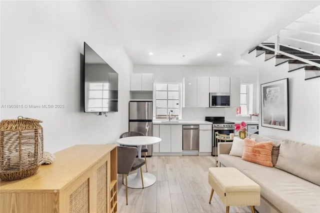a living room with furniture a flat screen tv and kitchen view