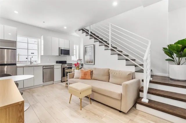 a living room with stainless steel appliances furniture and a kitchen view