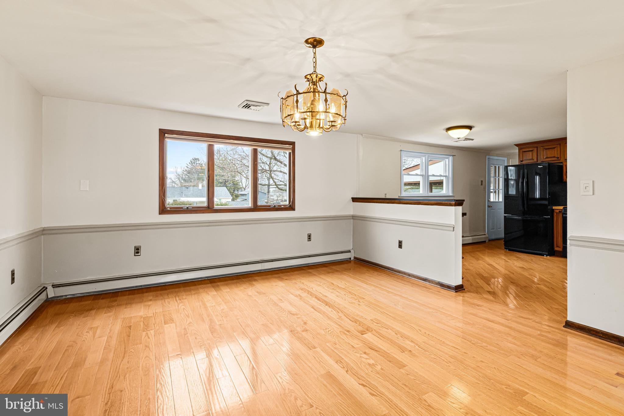 1413 Foster Road Warminster, PA 18974 - Photo 12 of 30 a big room with wooden floor a chandelier a kitchen view and a window