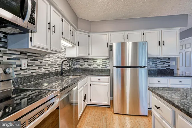 a kitchen with stainless steel appliances granite countertop a refrigerator stove and sink