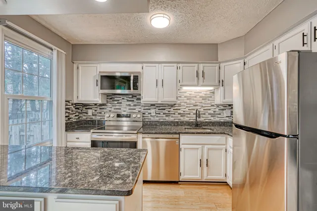 a kitchen with stainless steel appliances granite countertop a stove and a refrigerator