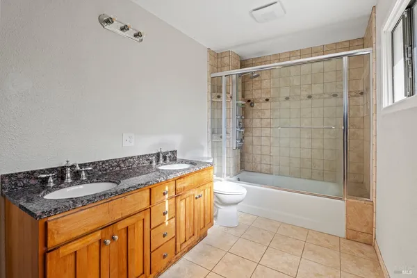 a bathroom with a granite countertop sink a toilet a mirror and shower