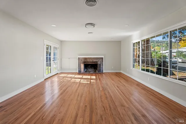 a view of empty room with wooden floor and fireplace