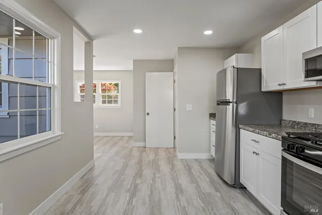 a view of kitchen with stainless steel appliances wooden floor and cabinets