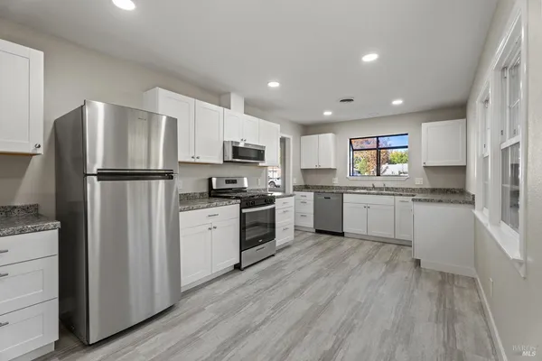 a kitchen with white cabinets and white appliances