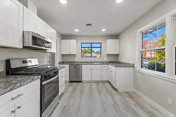 a kitchen with stainless steel appliances granite countertop a stove a sink and a microwave