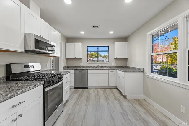 a kitchen with stainless steel appliances granite countertop a stove a sink and a microwave