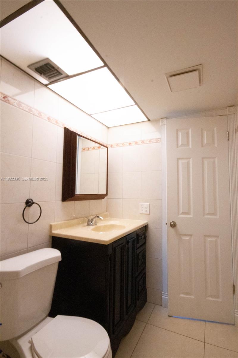 3000 Northwest 48th Terrace, Unit 322 Lauderdale Lakes, FL 33313 - Photo 14 of 15 a bathroom with a toilet a sink and mirror