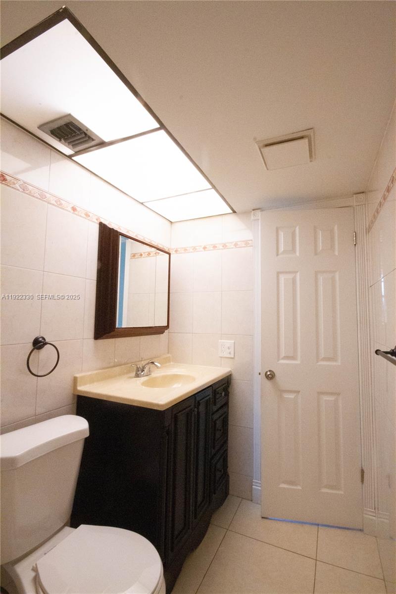 3000 Northwest 48th Terrace, Unit 322 Lauderdale Lakes, FL 33313 - Photo 15 of 15 a bathroom with a toilet a sink and mirror