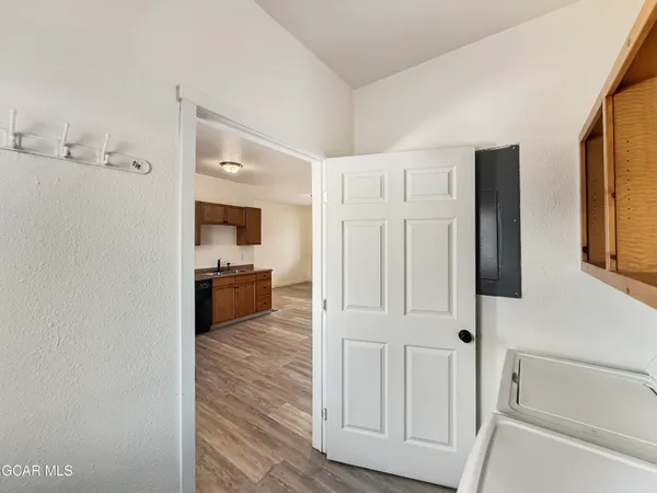 a view of a hallway with a kitchen space with wooden floor and electronic appliances