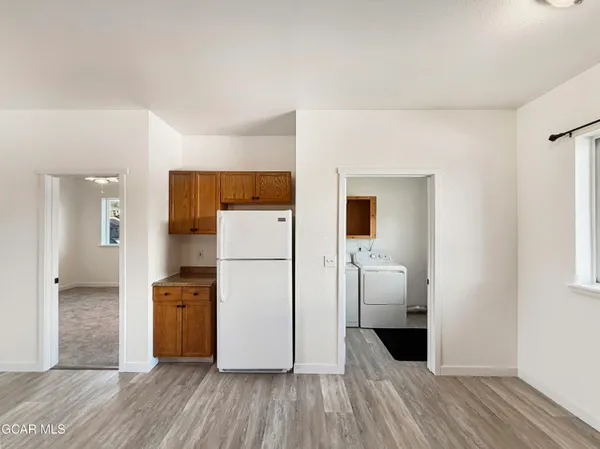 a kitchen with white cabinets and wooden floor