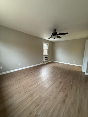 a view of wooden floor and a ceiling fan in a room