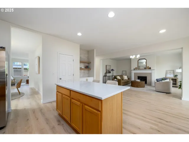 a kitchen with stainless steel appliances kitchen island granite countertop a refrigerator a stove top oven a sink dishwasher and white cabinets with wooden floor