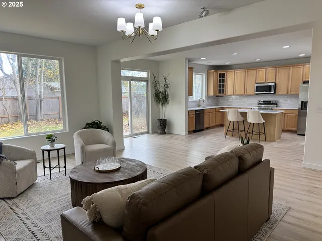 a living room with furniture kitchen view and a large window