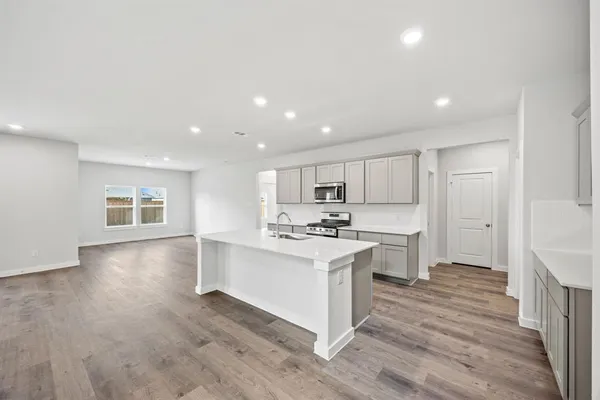 a kitchen with stainless steel appliances a stove top oven a sink a refrigerator and white cabinets