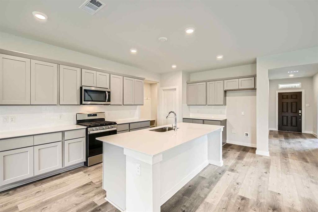 736 Vineyard Way Forney, TX 75126 - Photo 8 of 40 a kitchen with white cabinets and white appliances