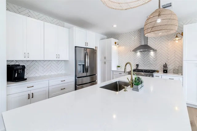 a kitchen with stainless steel appliances a stove a refrigerator and white cabinets