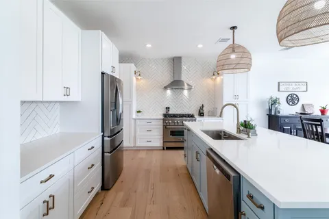 a kitchen with stainless steel appliances a sink dishwasher a refrigerator a stove top oven a counter space and cabinets