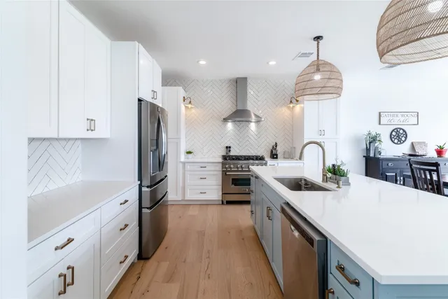 a kitchen with stainless steel appliances a sink dishwasher a refrigerator a stove top oven a counter space and cabinets