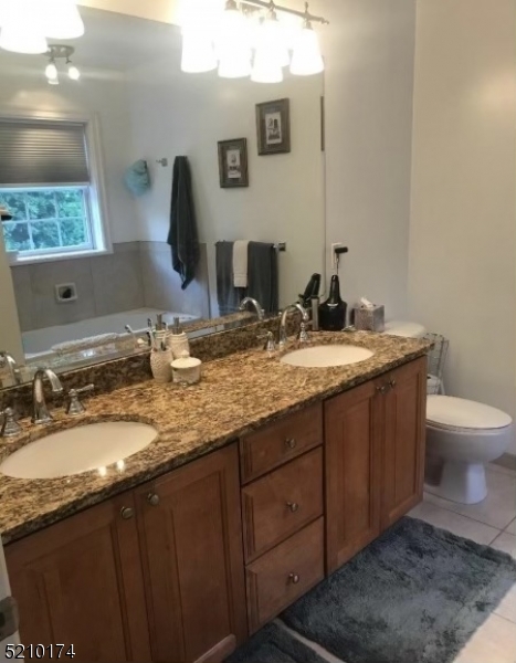 453 Springfield Avenue Berkeley Heights, NJ 07922 - Photo 10 of 13 a bathroom with a granite countertop sink a large mirror and a toilet