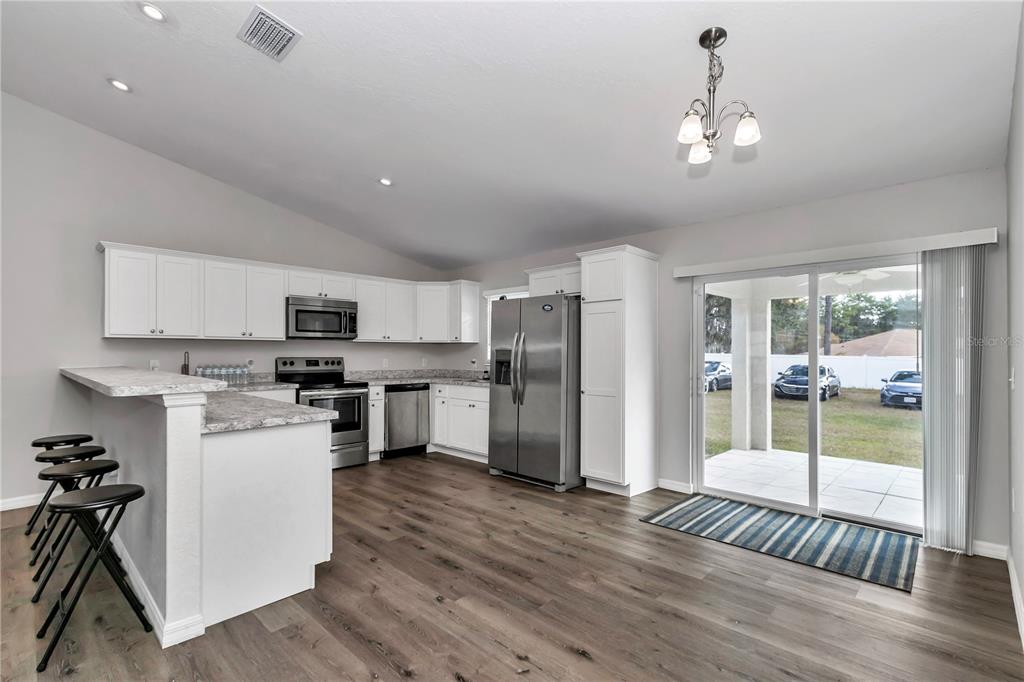 14 Maple Run Ocala, FL 34472 - Photo 7 of 43 a open kitchen with stainless steel appliances granite countertop a refrigerator oven a sink dishwasher a stove and white cabinets with wooden floor