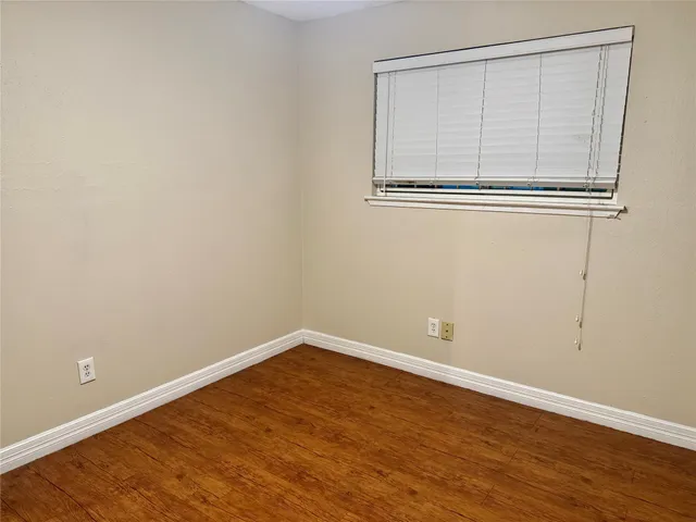 an empty room with wooden floor and a window