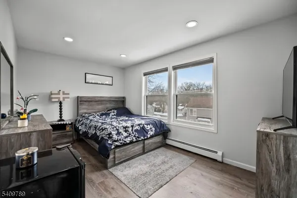 a bedroom with a bed wooden floor and a large window