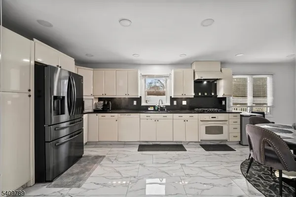 a kitchen with granite countertop a refrigerator stove top oven and sink