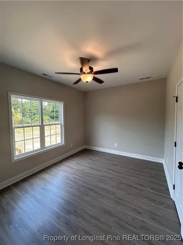 an empty room with wooden floor fan and windows