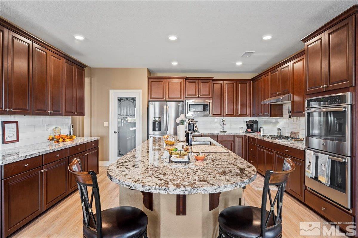 200 Noble Metal Court Reno, NV 89521 - Photo 10 of 39 a kitchen with stainless steel appliances granite countertop wooden cabinets granite counter tops and a refrigerator