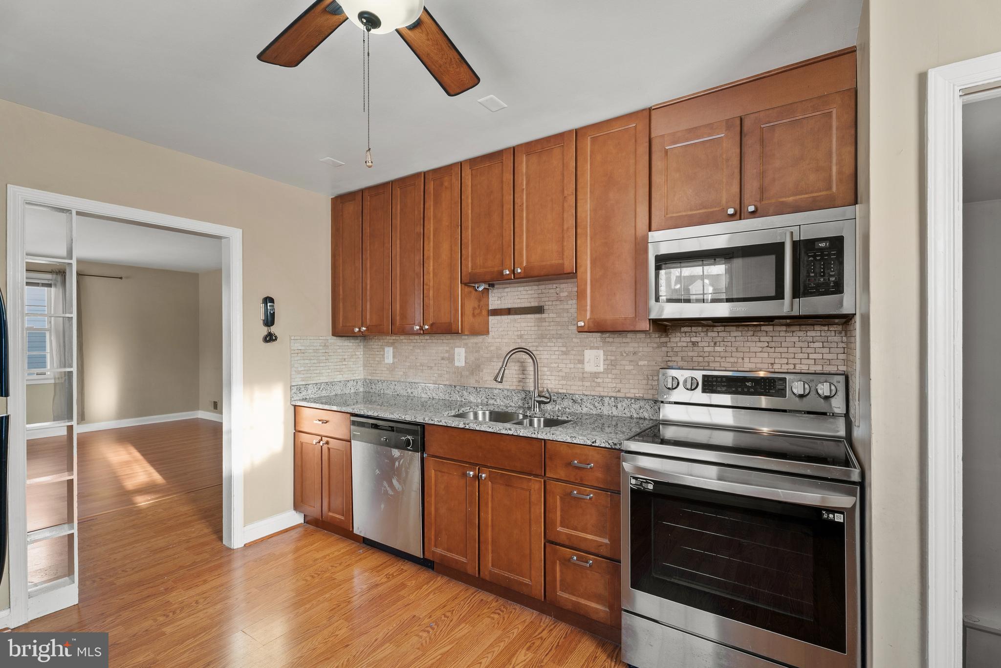 3823 Byfield Road Gwynn Oak, MD 21207 - Photo 9 of 37 a kitchen with granite countertop wooden cabinets stainless steel appliances and a counter space