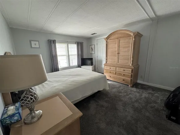 a bedroom with a bed lamp and a large window