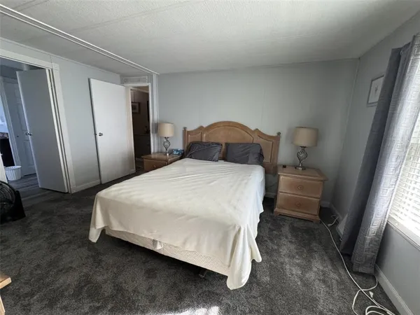 a bedroom with a bed a mirror with wooden floor