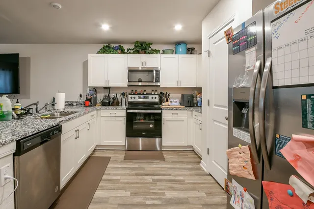 a large kitchen with stainless steel appliances kitchen island granite countertop a sink and cabinets