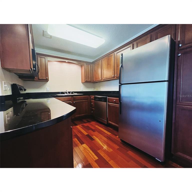 4876 South Conway Road, Unit 94 Orlando, FL 32812 - Photo 8 of 13 a kitchen with stainless steel appliances granite countertop a refrigerator and a sink