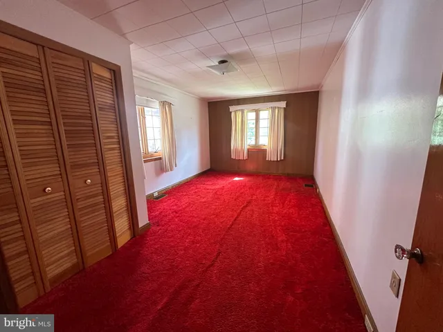 a view of an empty room with windows and dresser